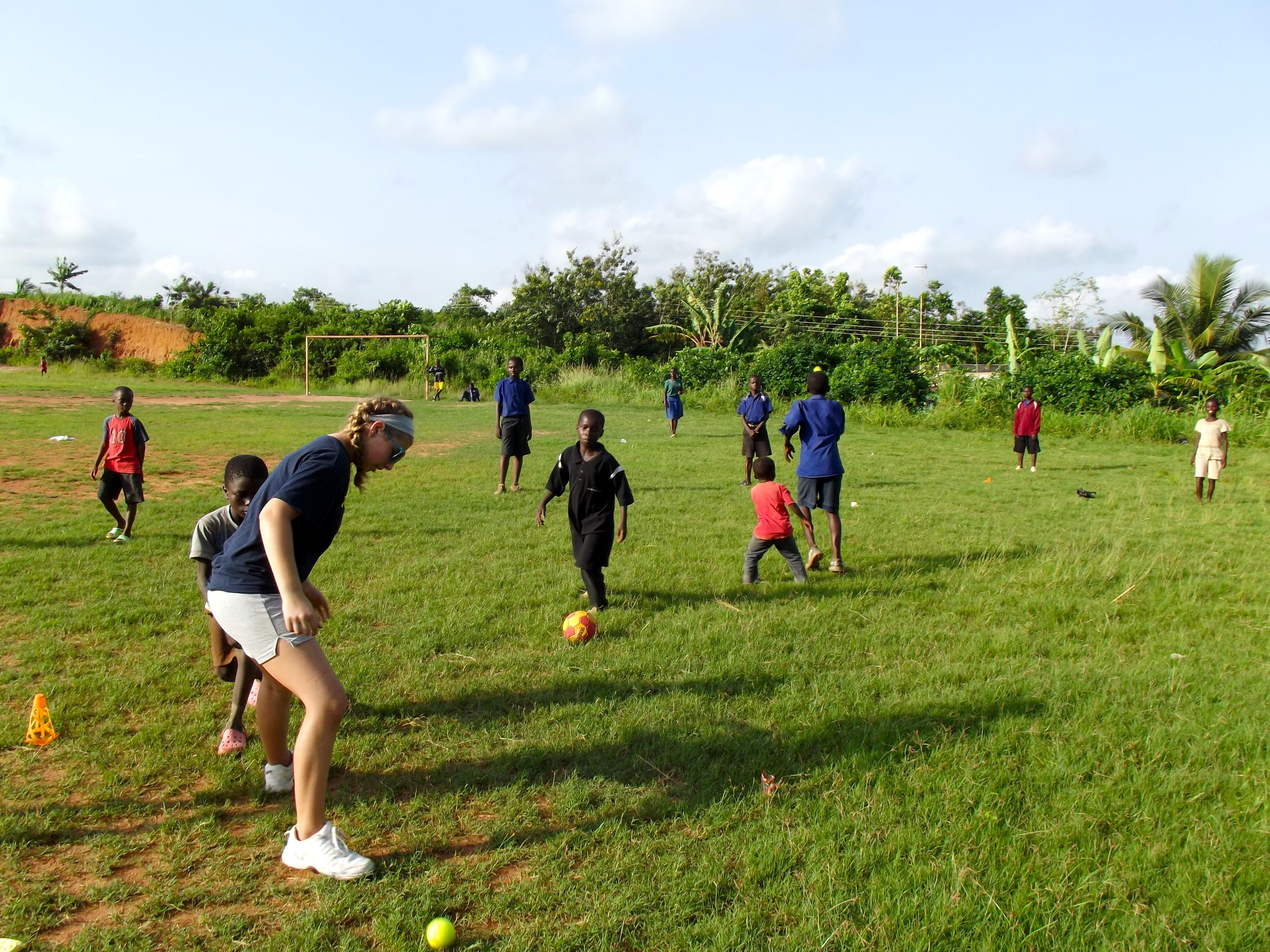 A teenage football volunteer coach in Ghana plays a friendly game with her young students. Projects Abroad volunteers taking part in football coaching for high school students in Ghana help improve the skills of their students.